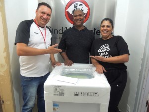 Fabiano da Silva Trindade, ao centro, ganhador de uma máquina de lavar roupa, com a diretora  Elisa Araújo e o diretor Márcio Ribeiro de Almeida